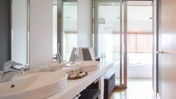 A modern bathroom with two sinks, a large mirror, and a sliding glass door leading to a balcony.