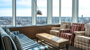Habitación en un rascacielos con vistas a la ciudad, que cuenta con un sofá, sillones y una mesa de centro.