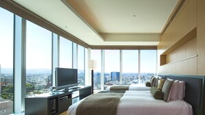 Habitación de hotel moderna con una amplia vista de la ciudad, televisión de pantalla plana, escritorio y una cama cómoda con varias almohadas.