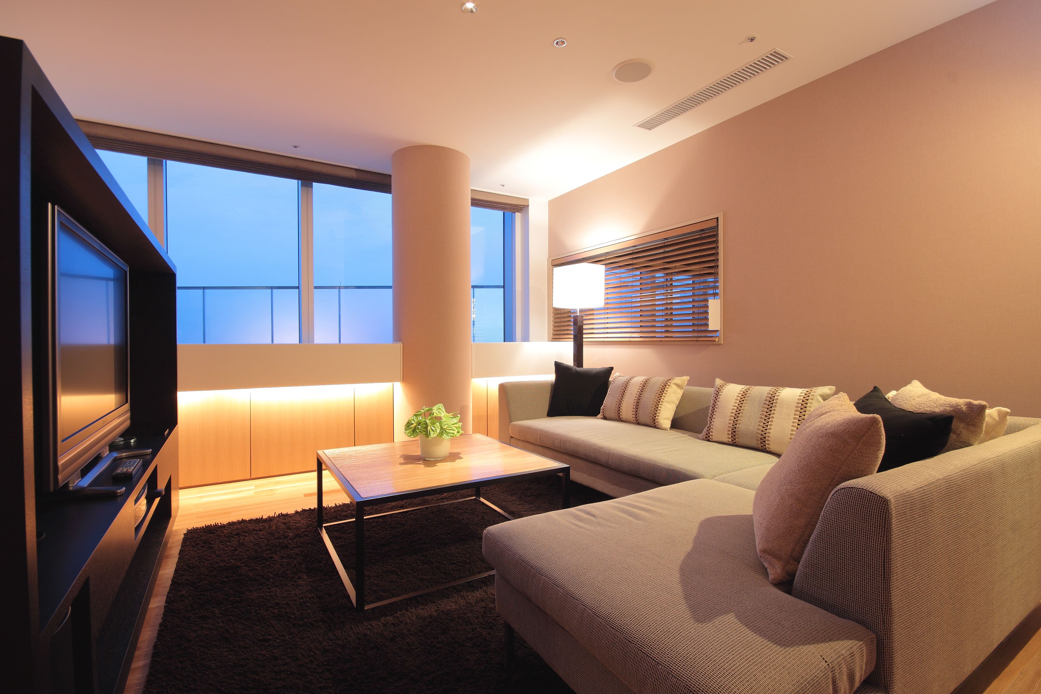 A modern living room with a sofa, a coffee table, a TV, and a large window.