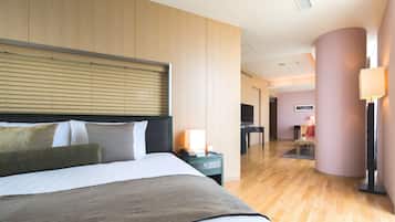 A hotel room with a bed, bedside table, lamp, and a view of the hallway.
