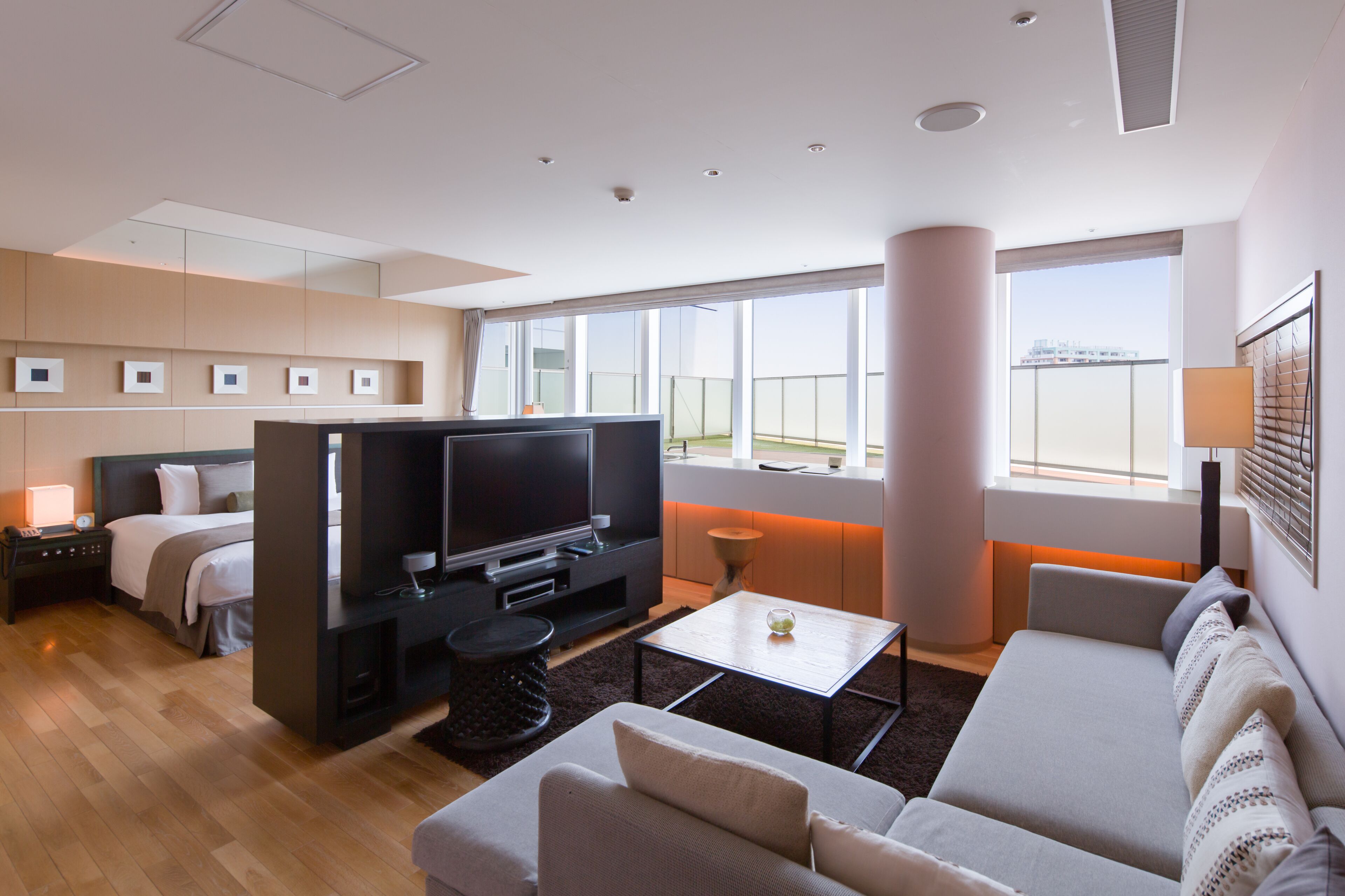 Ein modernes Hotelzimmer mit einem großen Bett, einem Fernseher, einer Couch und einem Balkon mit Blick auf die Stadt.