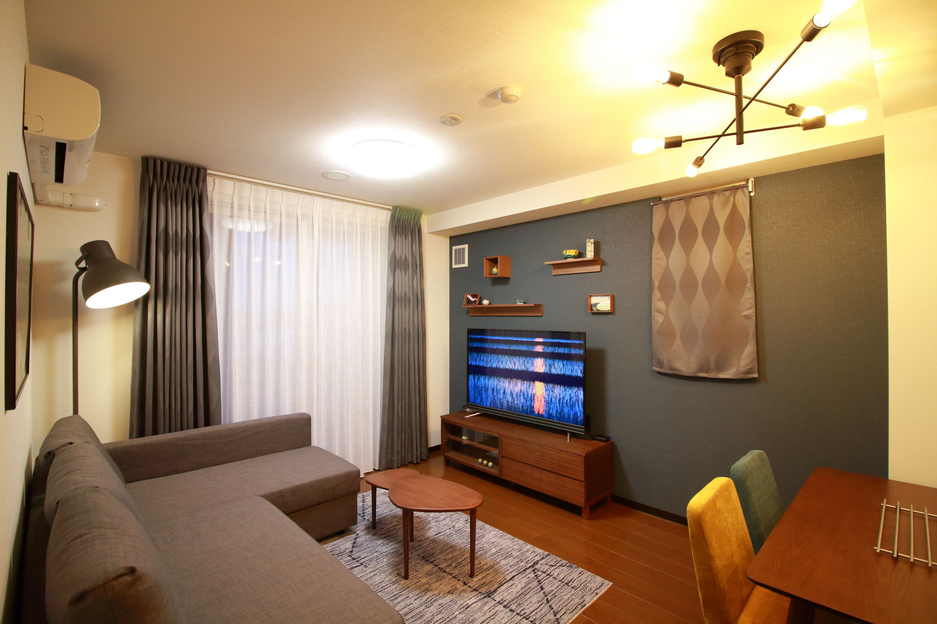 Una sala de estar con sofá, mesa de centro, televisor y mesa de comedor con sillas.