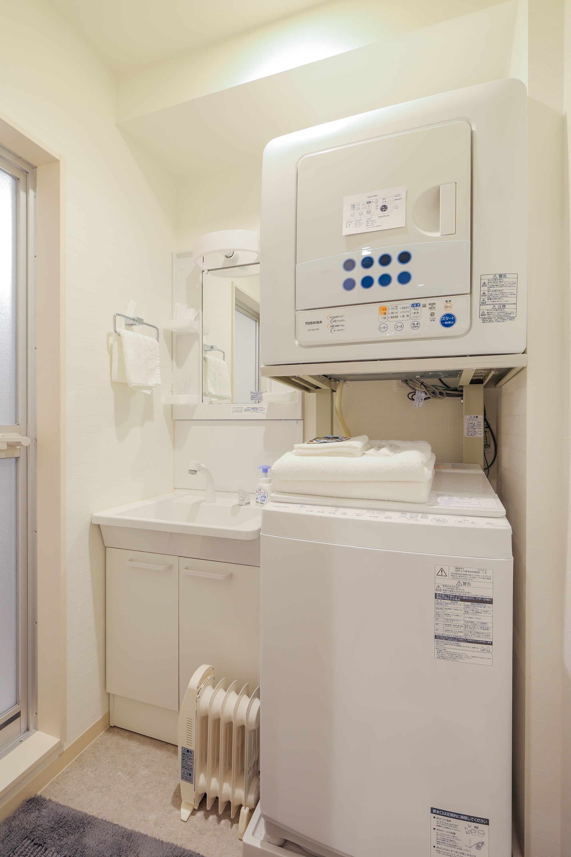 Een badkamer met een witte wastafel, een spiegel, een handdoekrek en een witte verwarming.