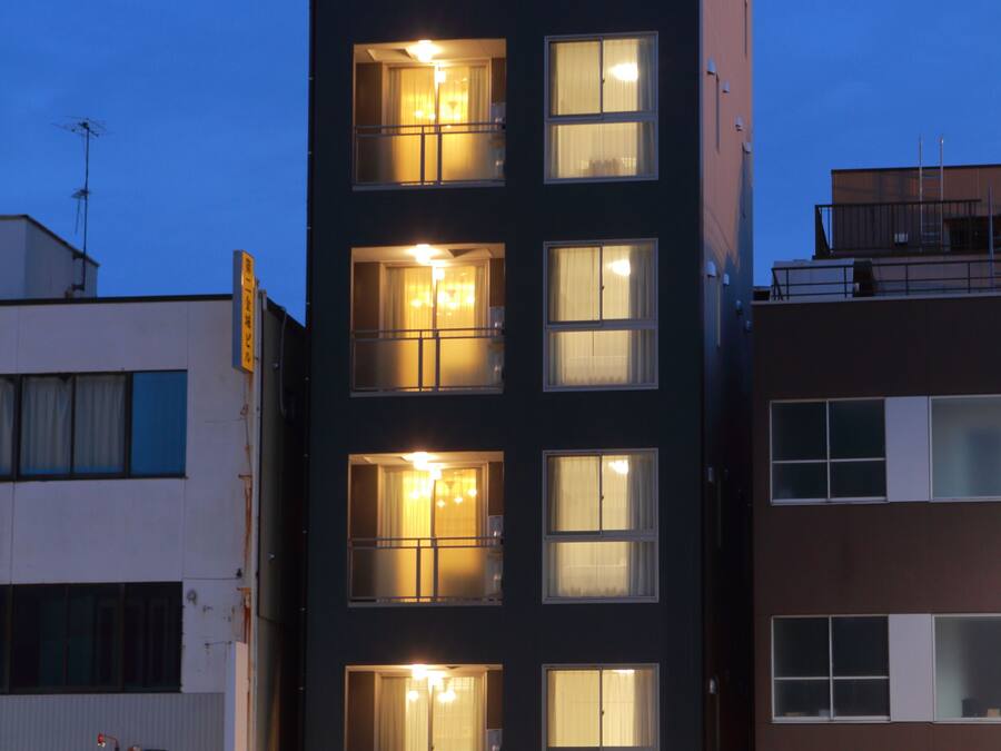A modern multi-story building with illuminated windows and a visible storefront.