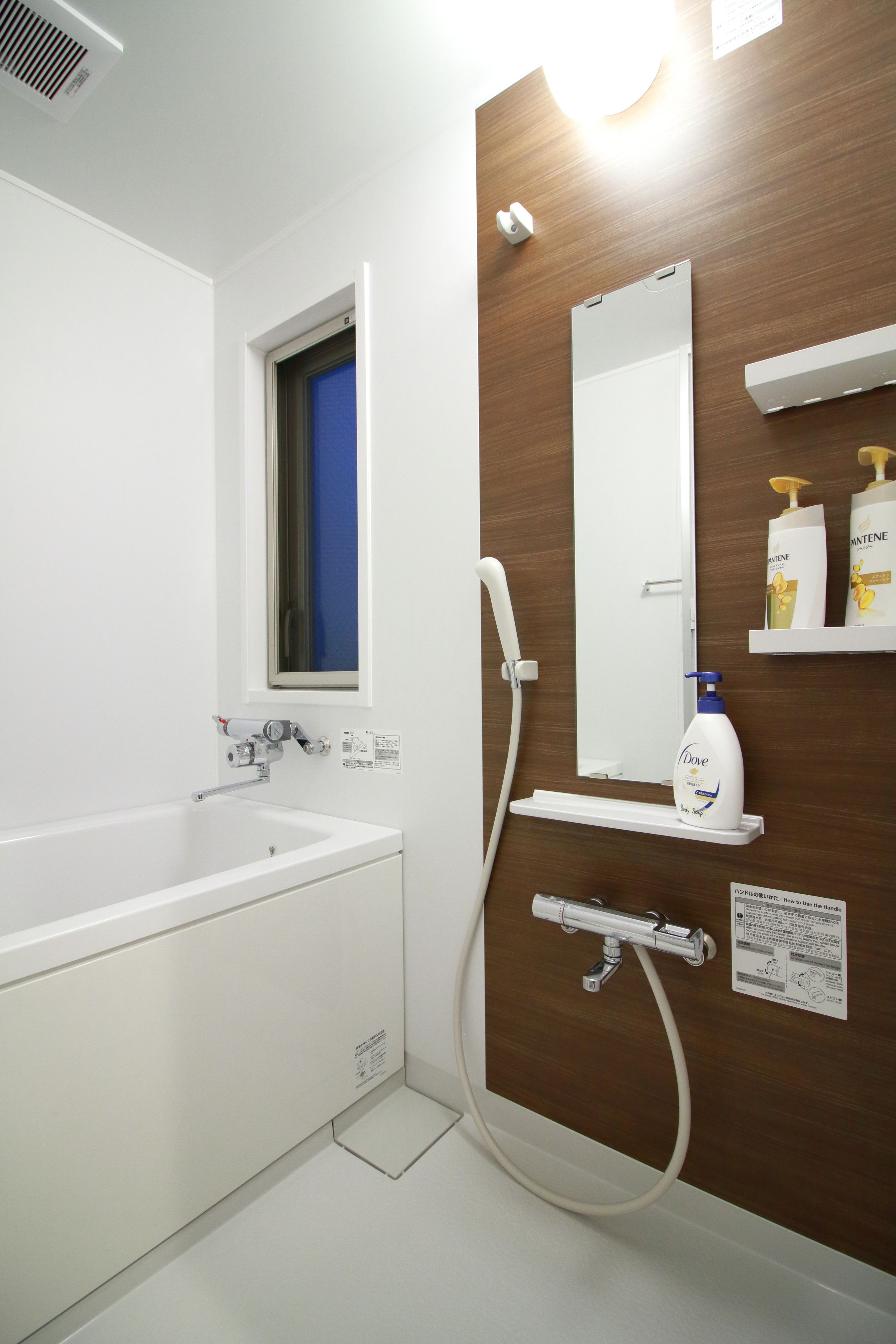 Un baño moderno con una bañera blanca, un espejo fijado a la pared y un cabezal de ducha.