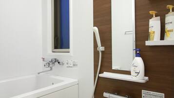 Un baño moderno con una bañera blanca, un espejo fijado a la pared y un cabezal de ducha.