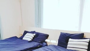 A hotel room with two beds, each with blue bedding and striped pillows.