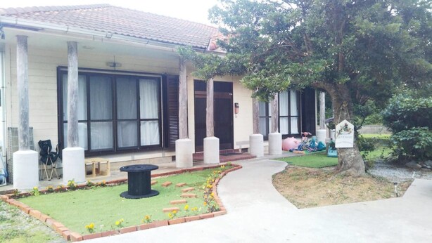 A house with a front porch, a small garden, and a tree.