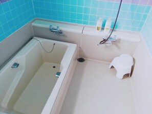 A bathroom with a bathtub, a toilet, and a shower area.