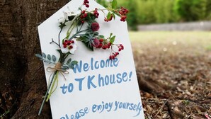 A welcome sign with a message and decorative flowers, placed on a tree trunk.