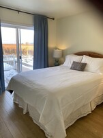 Habitación de hotel con una cama grande, una mesita de noche con lámpara y vistas a un paisaje nevado a través de una puerta corredera.