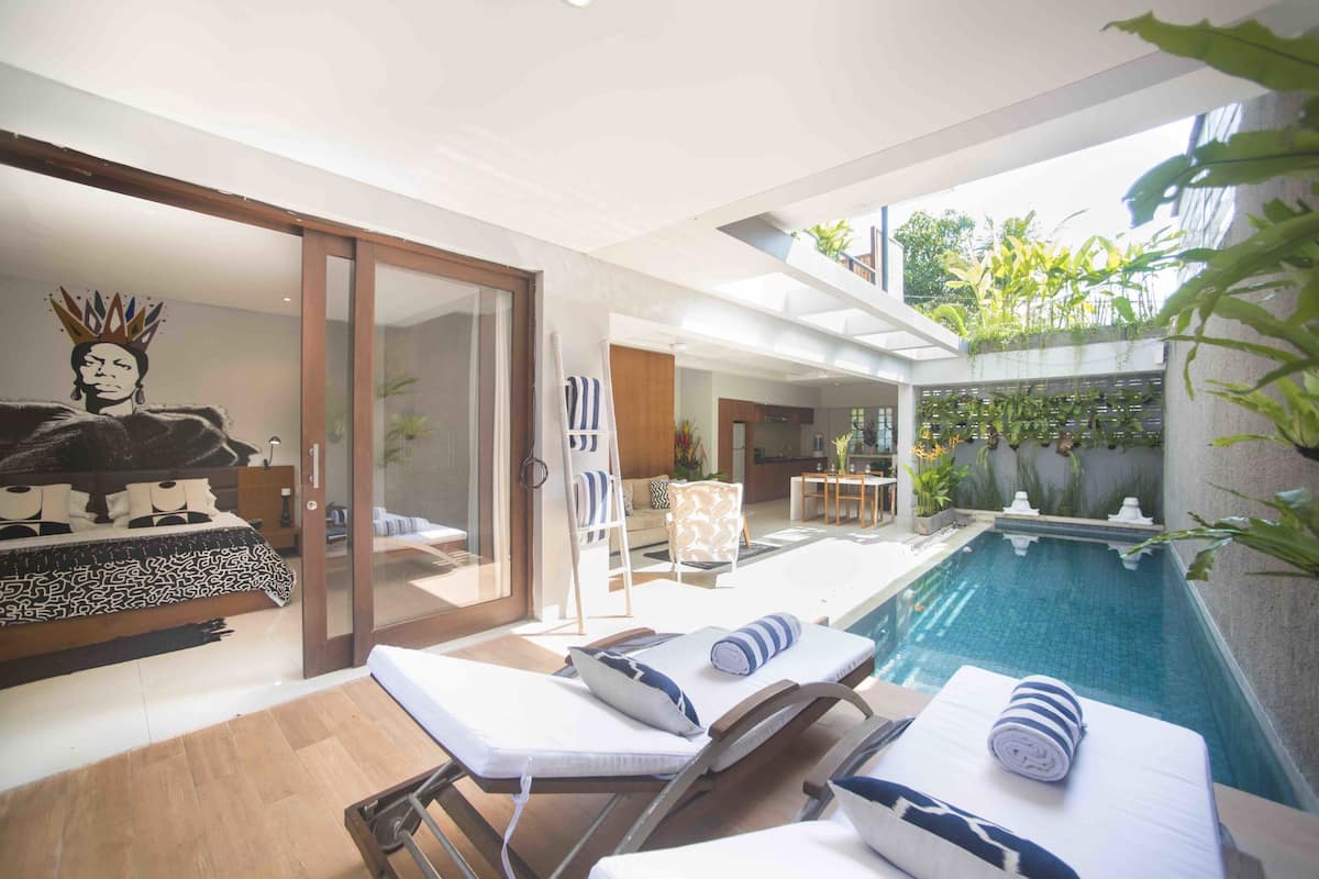 Un área moderna junto a la piscina con sillas de descanso, una piscina pequeña y un comedor.