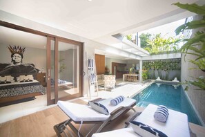 A modern poolside area with lounge chairs, a small pool, and a dining area.