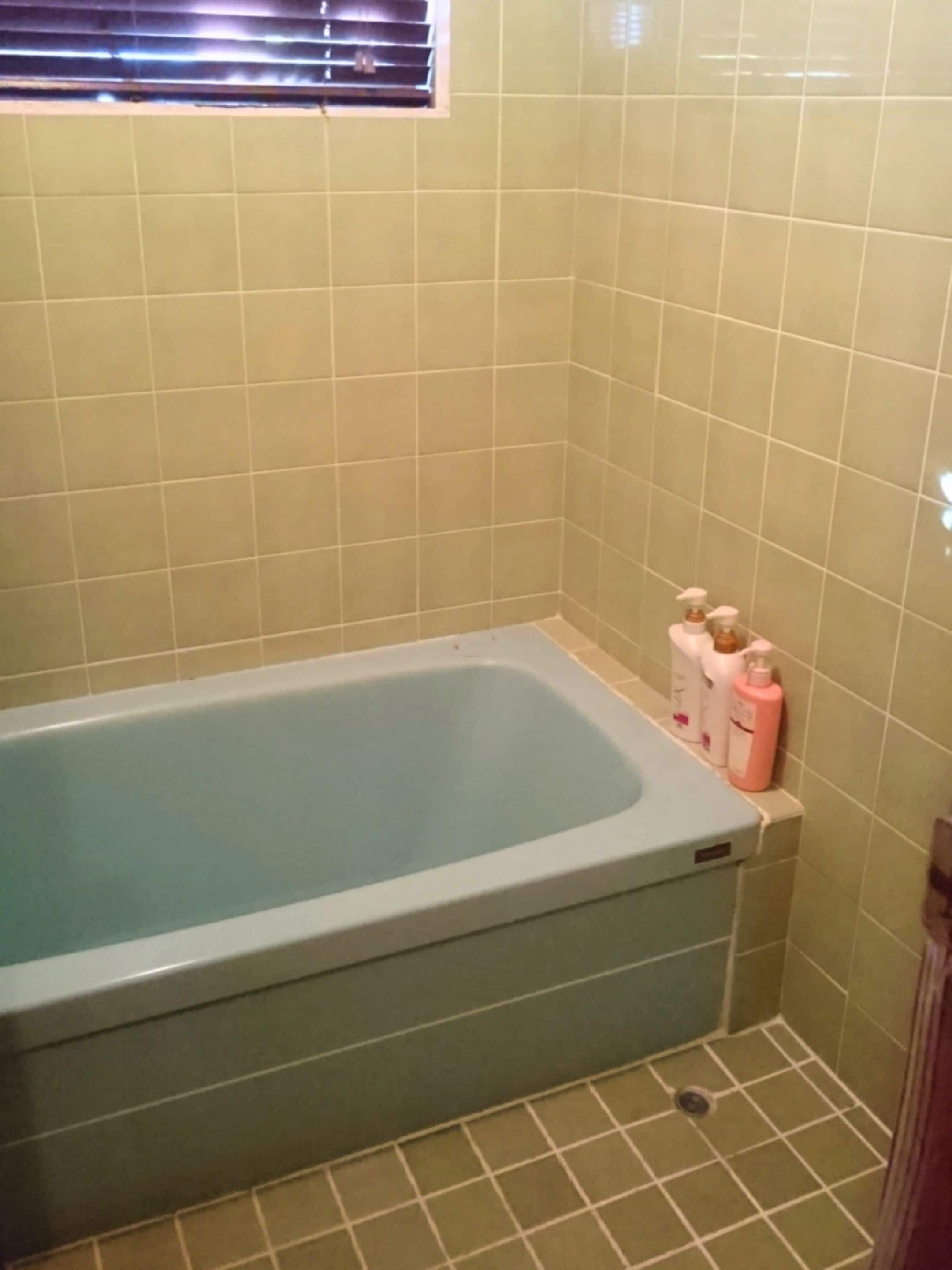 Un bagno con una vasca, pareti piastrellate e una finestra.