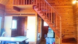 A wooden cabin interior with a staircase leading to a loft bedroom. - Private Beach House (Motobu)