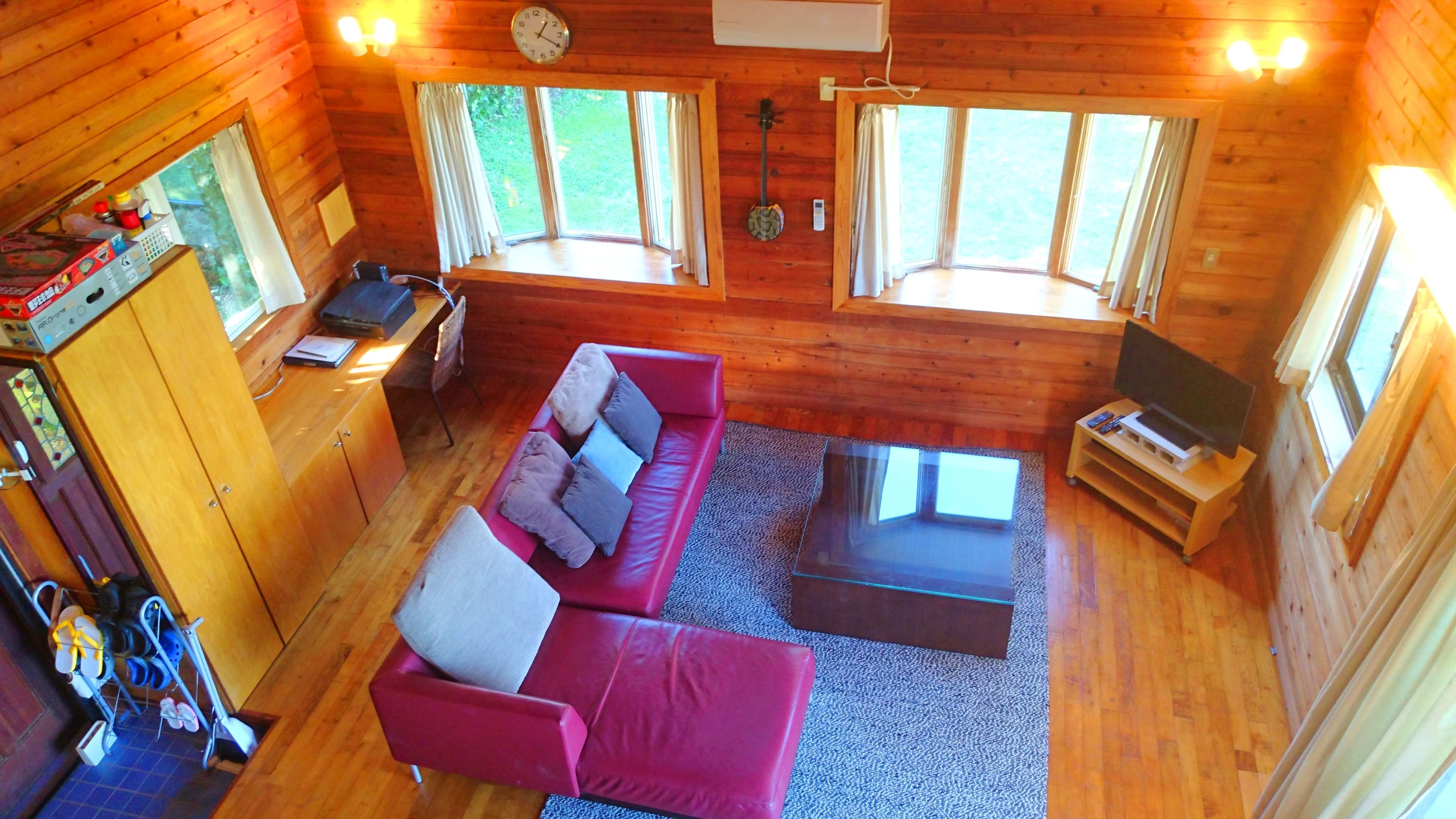 Una cabaña acogedora con un sofá rojo, un televisor y detalles de madera.
