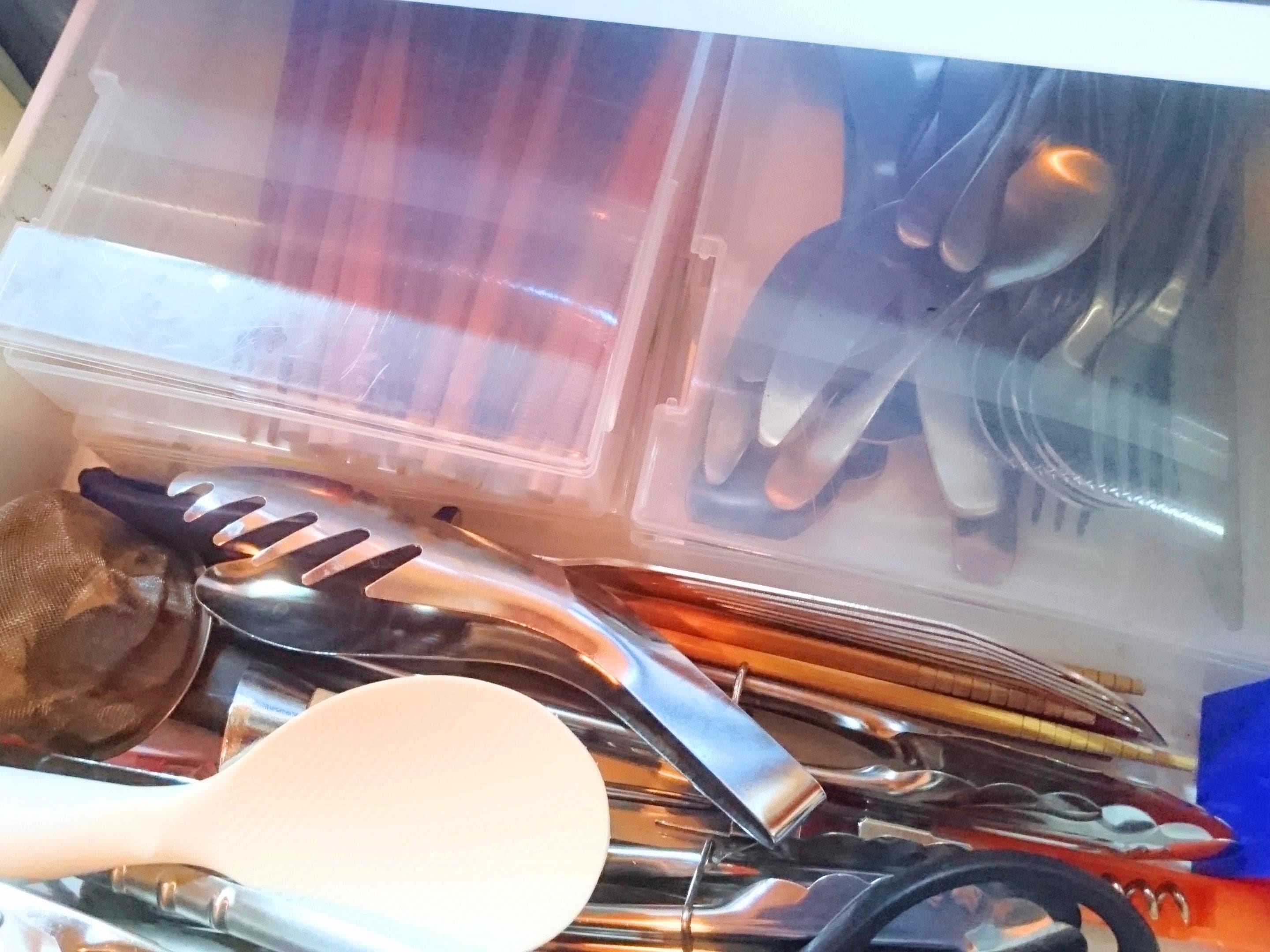 A plastic container with various kitchen utensils and a white spatula.