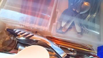 A plastic container with various kitchen utensils and a white spatula.