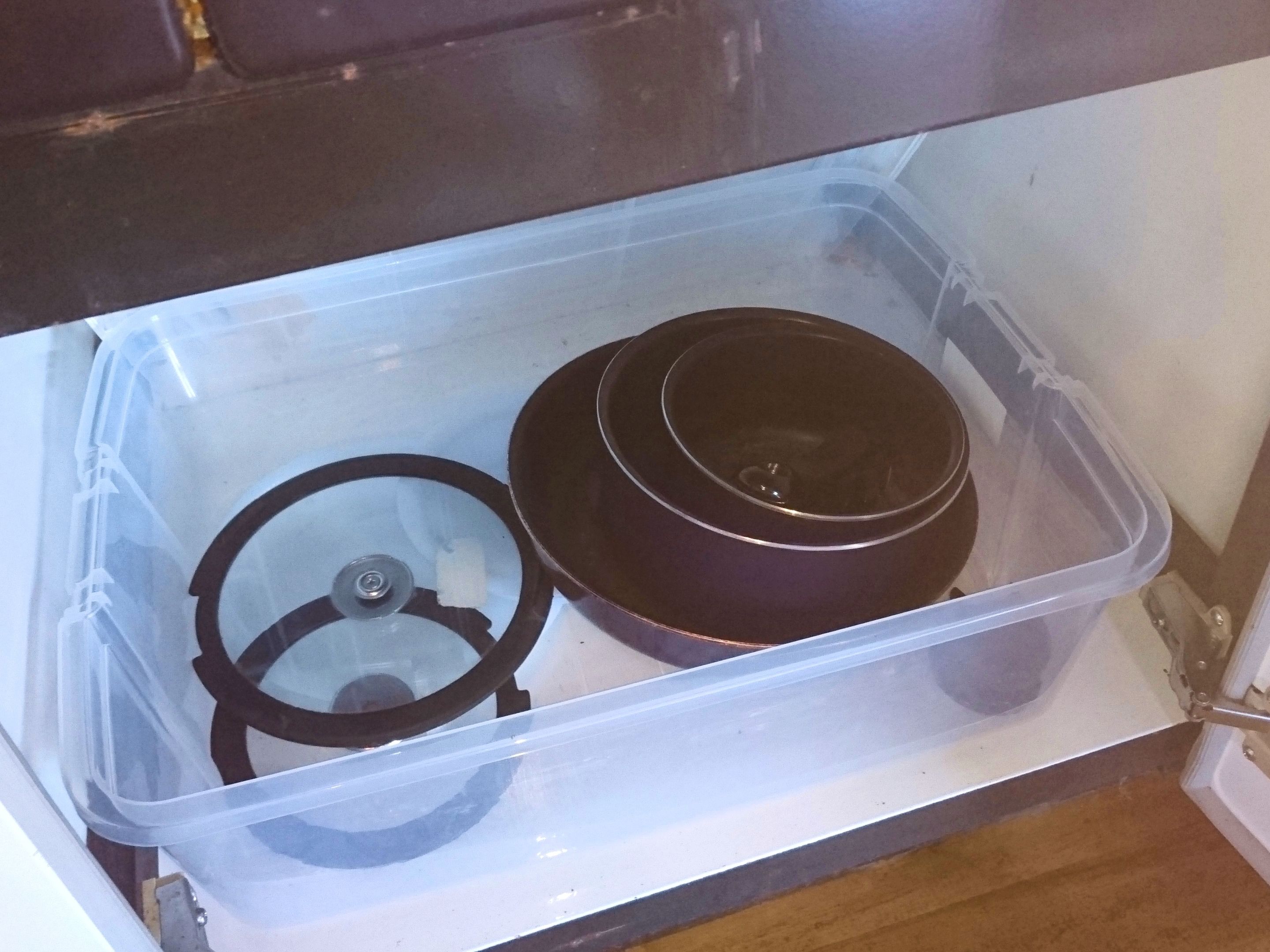 A clear plastic storage container with a lid and a black circular object inside.