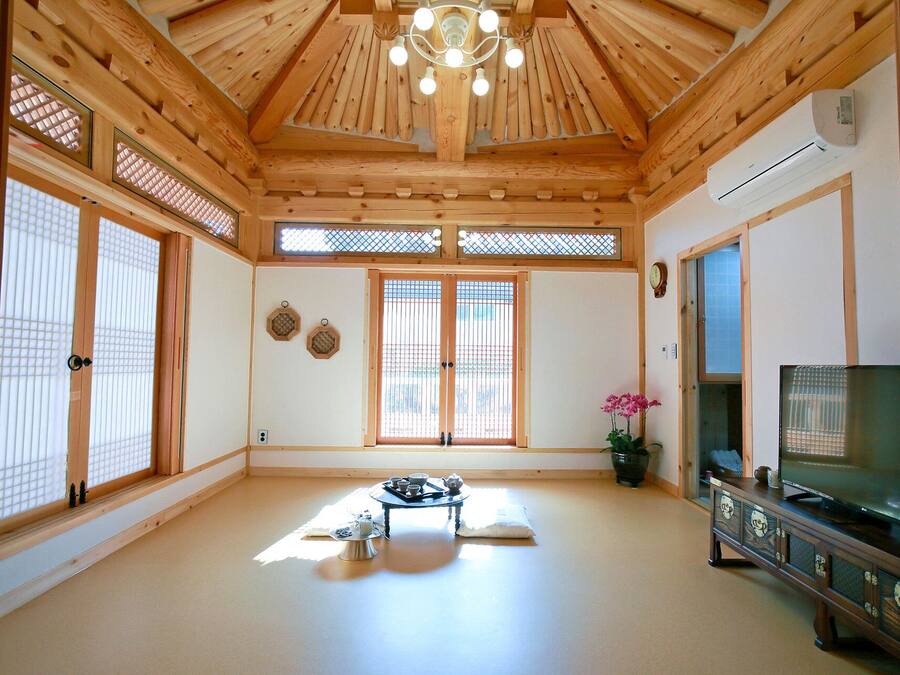 Una habitación tradicional japonesa con suelo de tatami, puertas correderas, televisión y ventilador de techo.