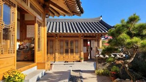 A traditional wooden building with a tiled roof, a wooden porch, and a stone pathway leading to the entrance. - Wiyeonjae Hanok Stay (Gyeongju)