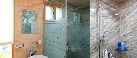 A bathroom with a wooden vanity, a sink, a glass shower enclosure, and a marble shower wall.