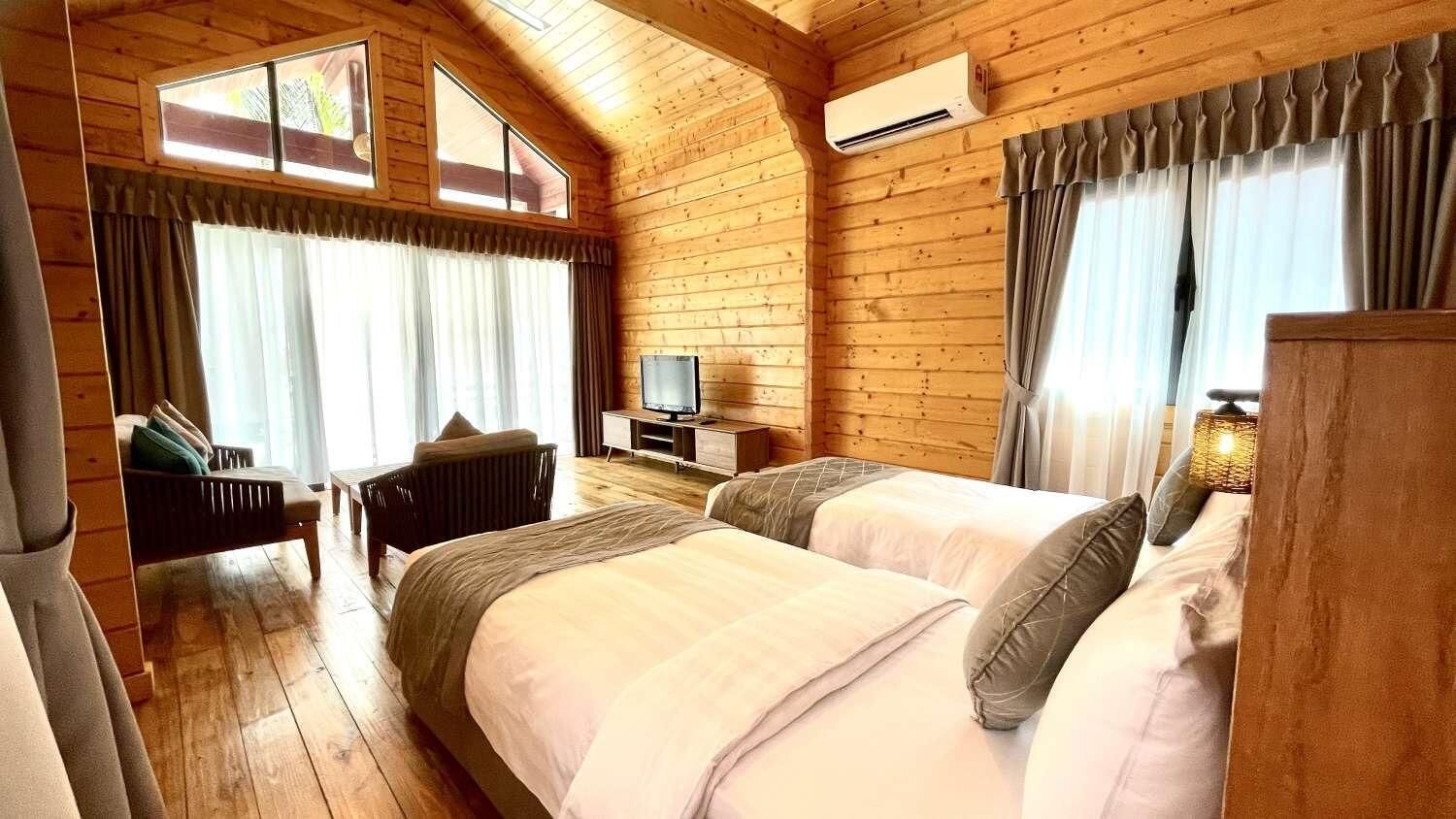 A cozy wooden cabin room with two beds, a TV, and a small table.