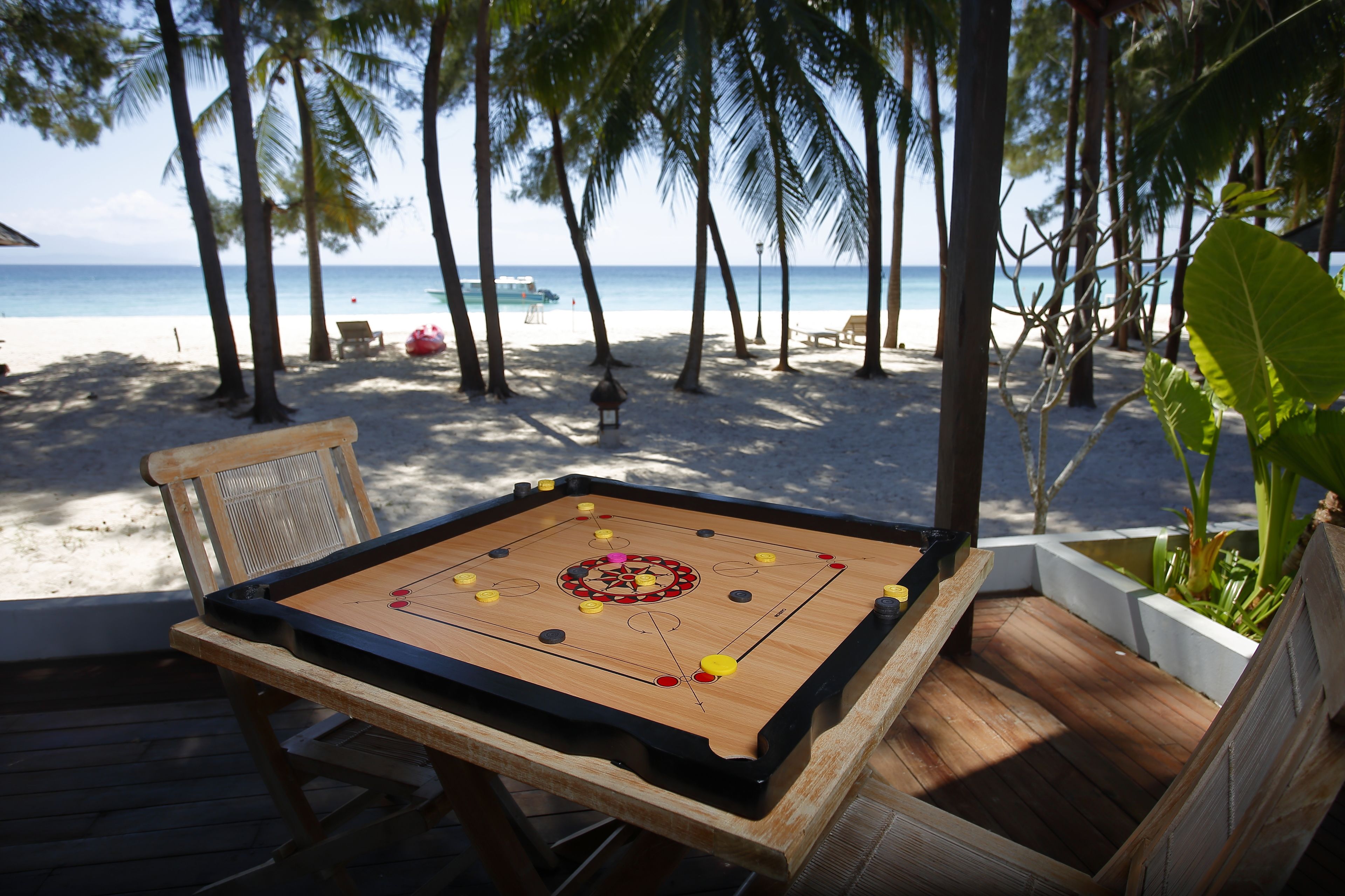 A foosball table on a wooden deck with a view of the beach and ocean.