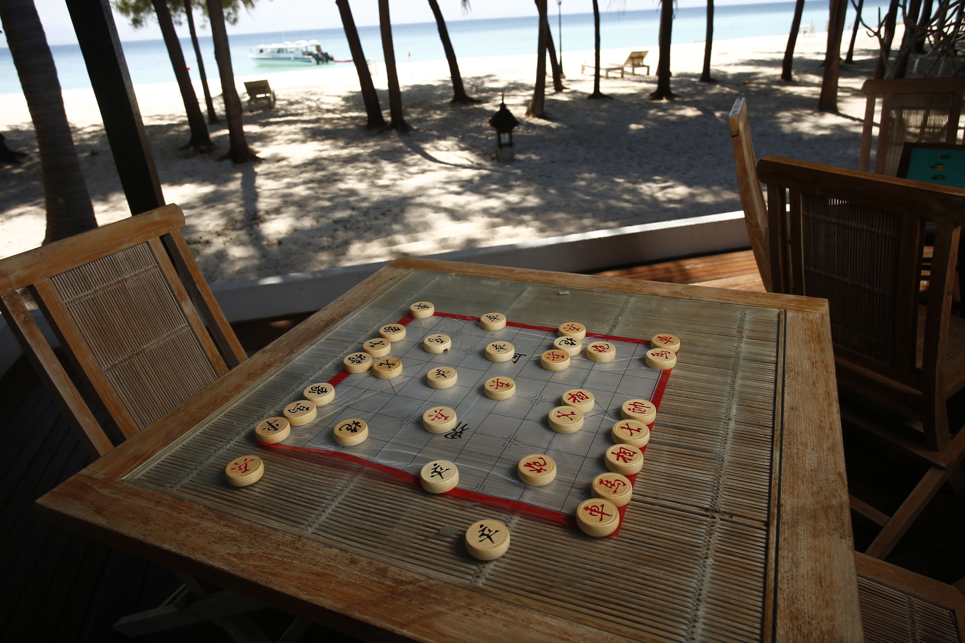 A Go board on a wooden table with a beach view in the background.