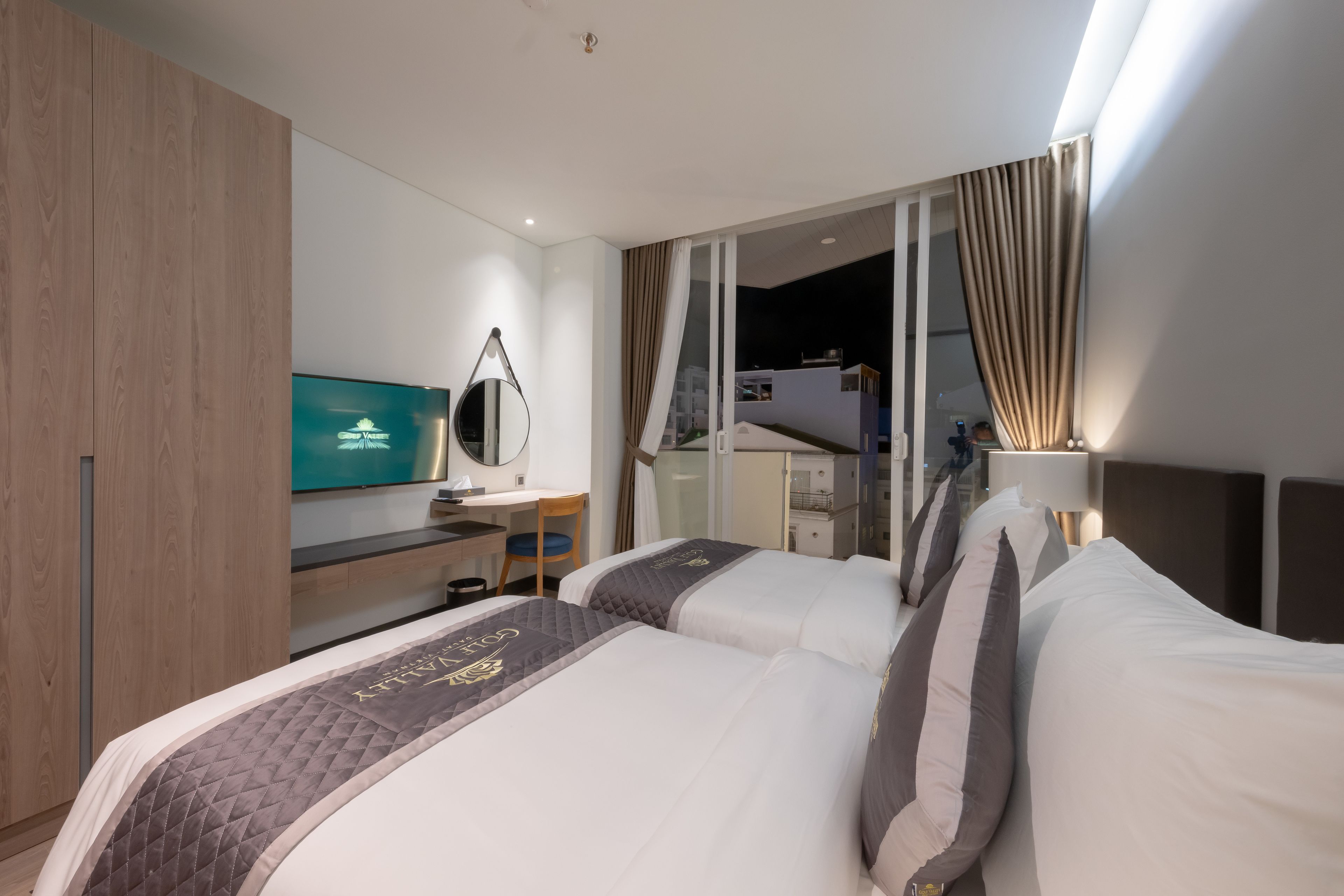Una habitación de hotel con dos camas, un escritorio, un televisor y vistas a la ciudad.