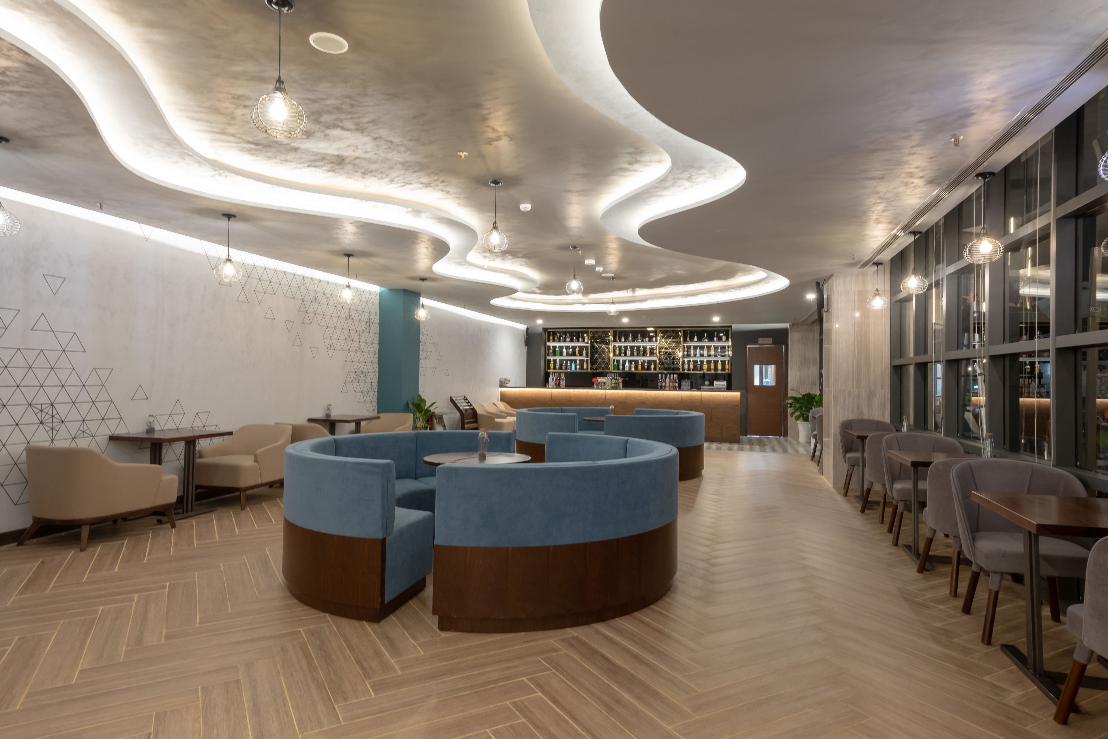 A modern lounge area with curved seating, a bar, and a patterned wall.
