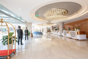 Un hall d’hôtel moderne avec un comptoir d’accueil, un lustre et un sol propre et bien ciré.