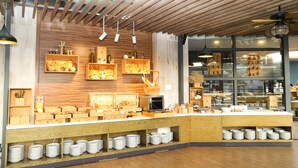 A breakfast buffet area with wooden shelves, a coffee machine, and various food items. - Nesta Valley Dalat Hotel - Golf Valley Hotel (Xuan Huong - Da Lat)