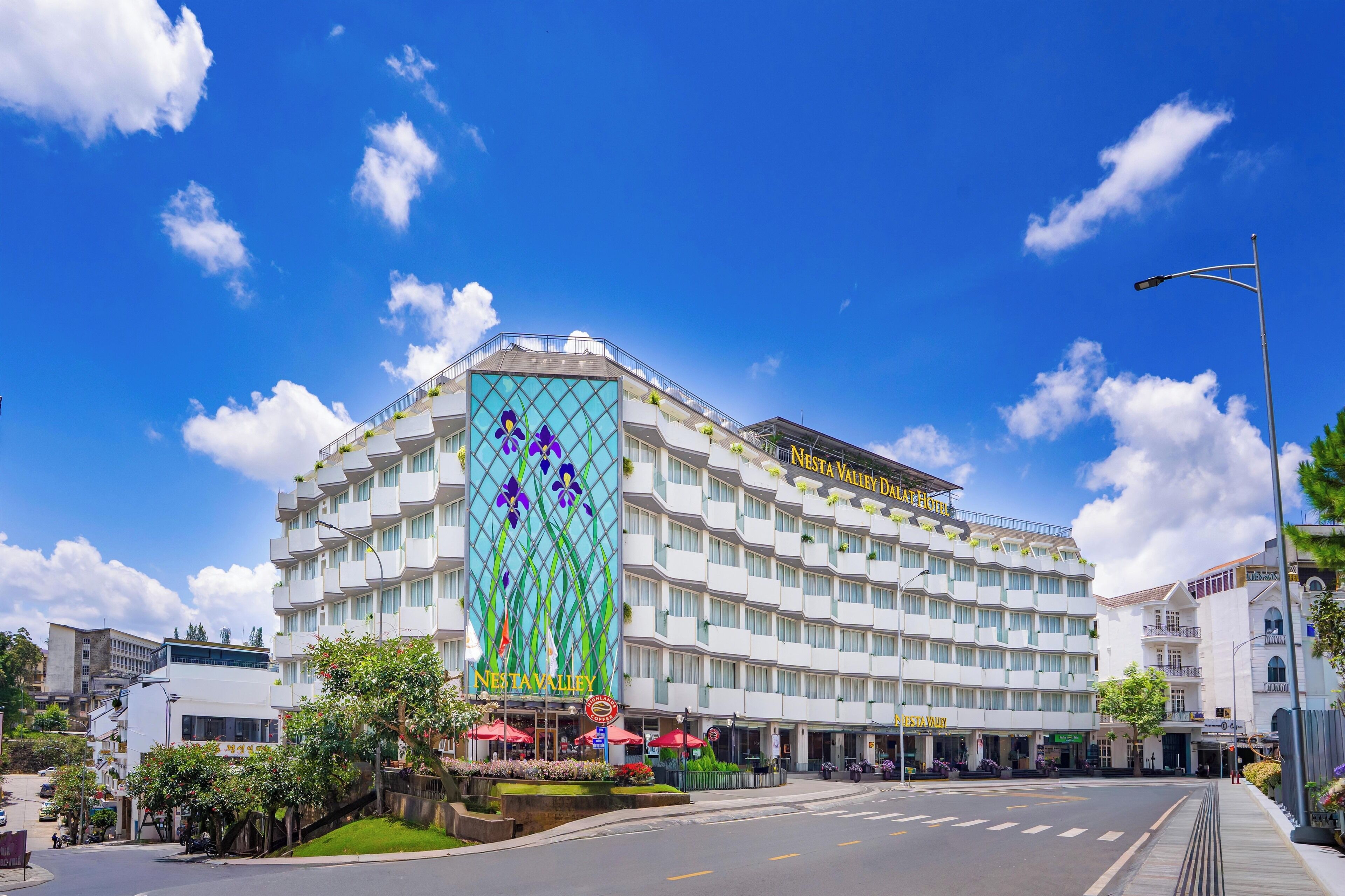Un hotel con una fachada distintiva de jardín vertical, varios balcones y un cielo azul despejado.
