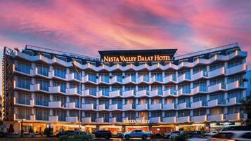 A multi-story hotel with a prominent sign reading 'NESTA VALLEY DALAT HOTEL.'