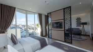 A modern hotel room with two beds, a large window with curtains, a city view, a TV, and a decorative wall panel. - Nesta Valley Dalat Hotel - Golf Valley Hotel (Xuan Huong - Da Lat)