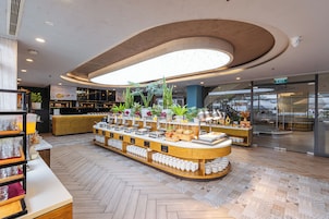 Un interior moderno con un área de buffet central, una estación de café y una señal de salida visible.