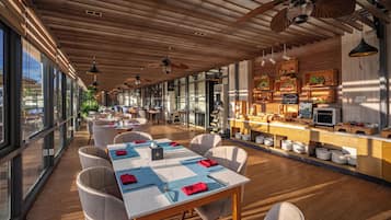 A restaurant with a long dining area, wooden ceiling, and large windows.