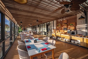 Un restaurant doté d’une grande salle à manger, d’un plafond en bois et de larges fenêtres.