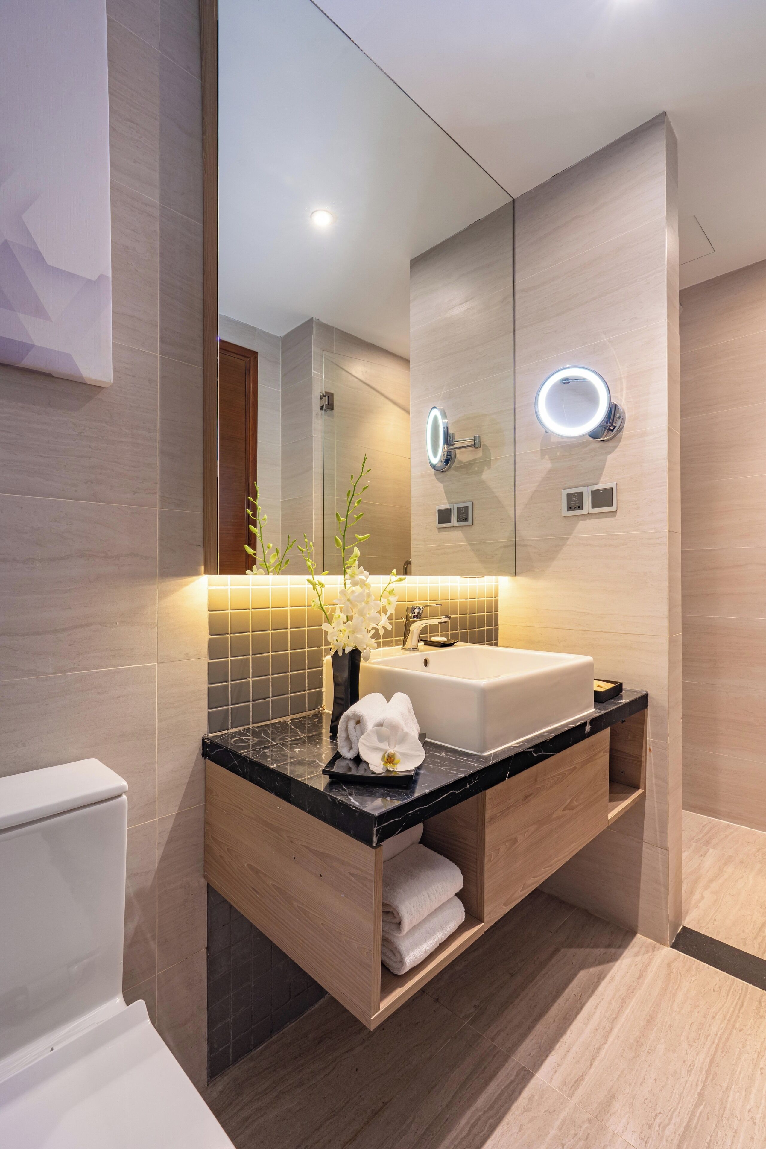 A modern bathroom with a large mirror, a sink, and a vanity with a towel rack.