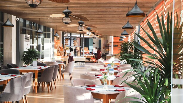A spacious restaurant with wooden tables and chairs, pendant lighting, and large windows. - Nesta Valley Dalat Hotel - Golf Valley Hotel (Xuan Huong - Da Lat)