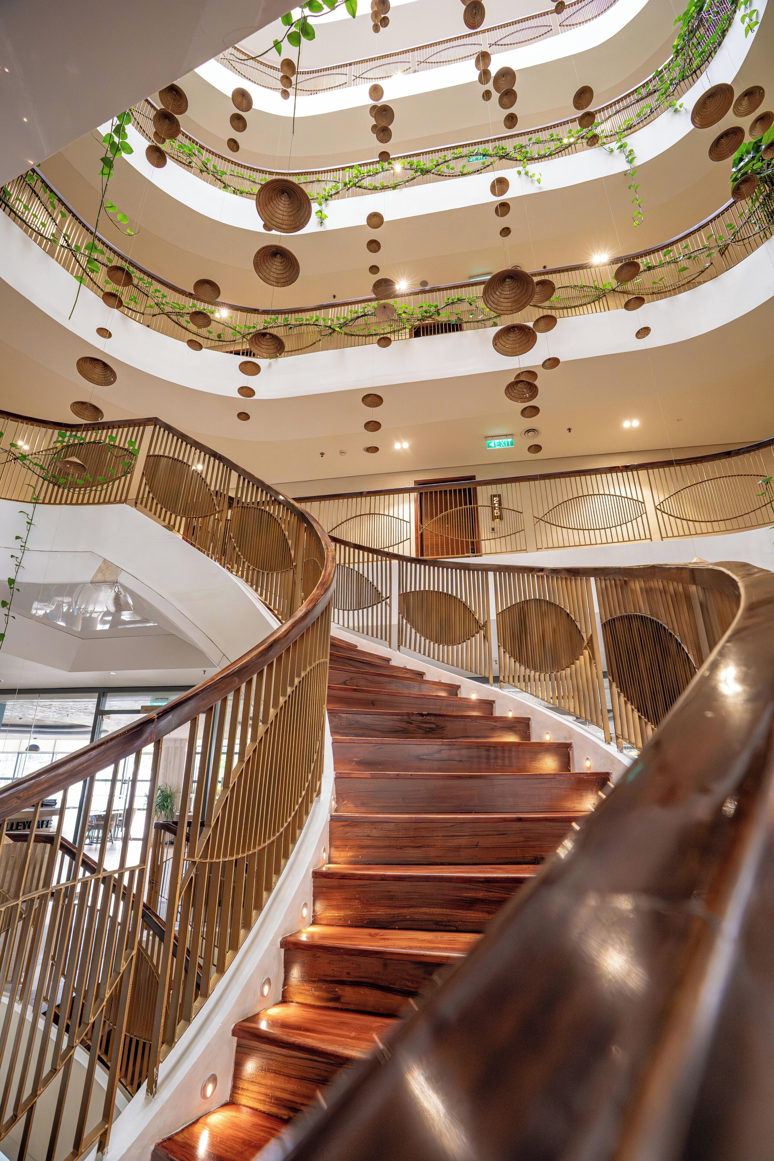 A multi-level interior with a wooden staircase, circular hanging baskets, and a curved railing design.