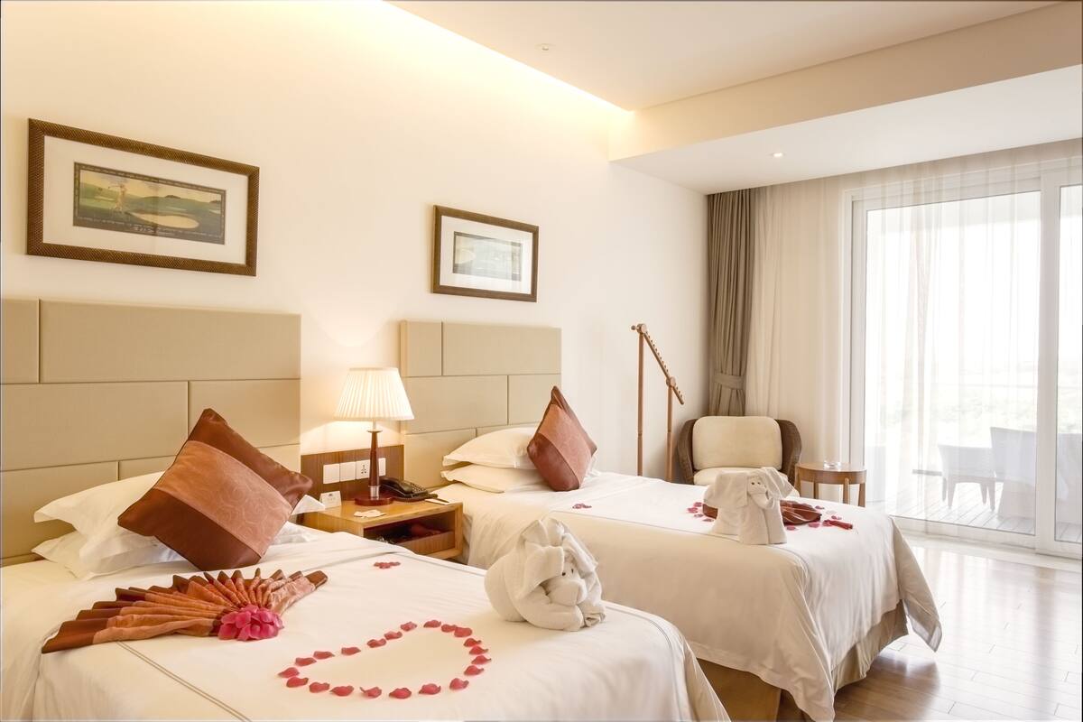 Een hotelkamer met twee bedden, een bureau, een stoel en een groot raam.