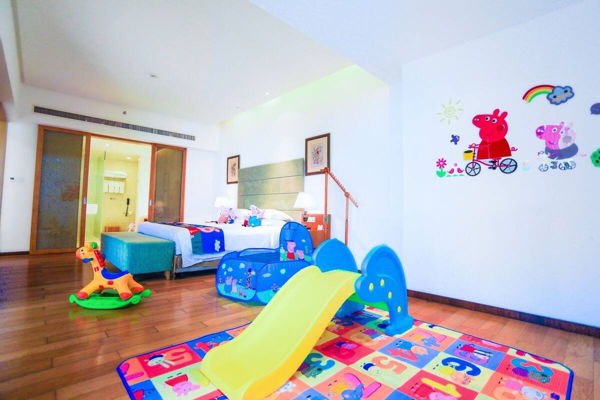Een kinderspeelruimte met een glijbaan, speelgoed en een bed met een kleurrijk dekbed.