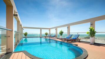 Una piscina al aire libre, sillones reclinables de piscina