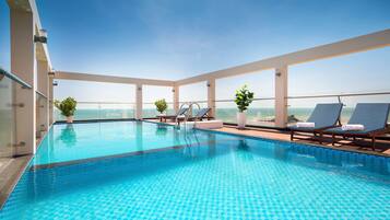 Una piscina al aire libre, sillones reclinables de piscina