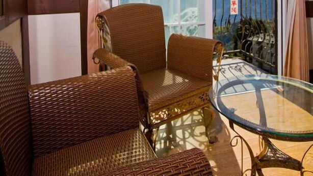 A balcony with wicker furniture, a glass table, and purple flowers. - Maple Leaf Holiday Villa (Ren'ai)