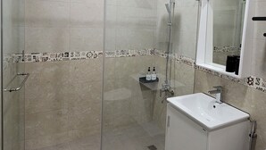 A modern bathroom with a glass-enclosed shower, a white sink, and a mirror above the sink. - Maple Leaf Holiday Villa (Ren'ai)