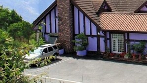 A traditional Tudor-style building with a steeply pitched roof, dormer windows, and a prominent red maple leaf symbol on the front. - Maple Leaf Holiday Villa (Ren'ai)